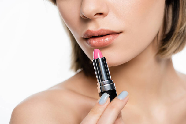 cropped view of young woman holding pink lipstick isolated on white - Foto, afbeelding
