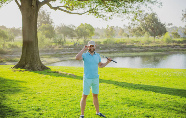Male golf player on professional golf course. Golfer man with golf club taking a shot. - Φωτογραφία, εικόνα