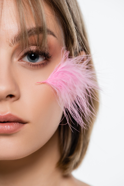 cropped view of sensual young woman with pink feather on face isolated on white - Foto, Imagen
