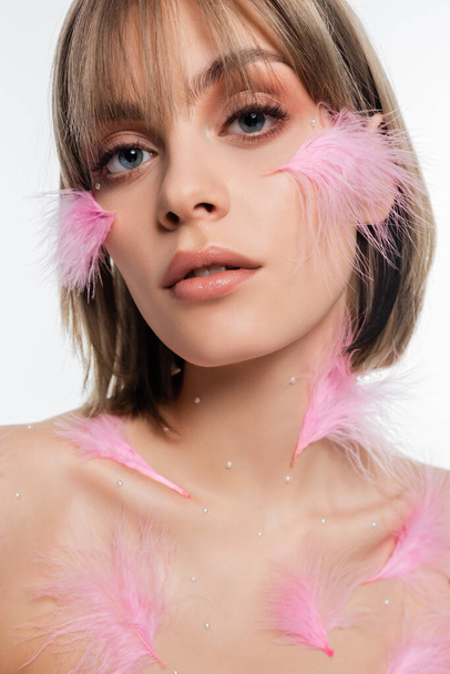 close up of young woman with decorative elements and pink feathers on face and body isolated on white - Foto, Imagen