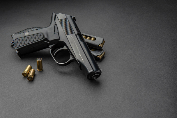 Pistol and cartridges for it on a dark background. A short-barreled weapon for self-defense. - Foto, Imagem