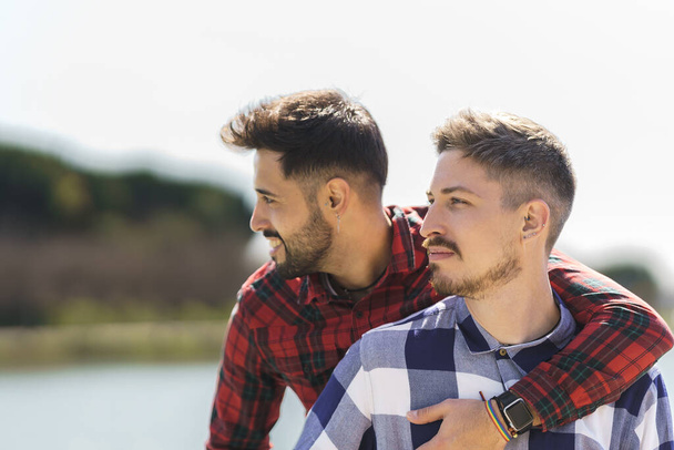 gay hugs from behind her boyfriend enjoying nature - Фото, изображение