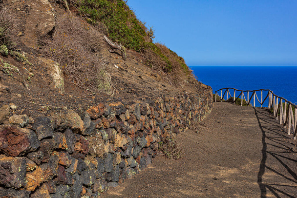 Путь к вулкану Монте-Неро в Линозе. Характерная сельская дорога с каменной стеной из лавы - Фото, изображение