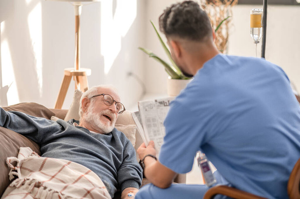 Caring caregiver entertaining male patient during the intravenous therapy - Foto, Imagem
