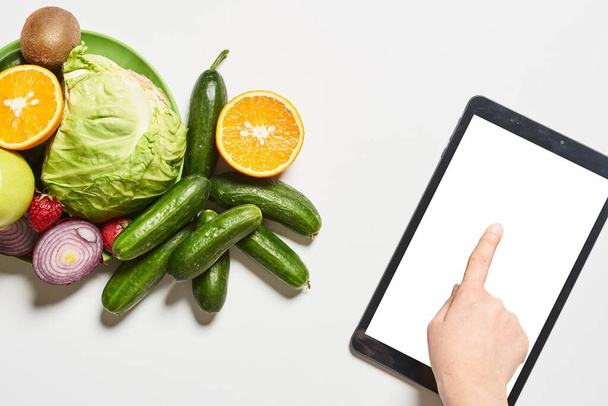 Organic vegetables, fruits and a person using tablet with a blan - Foto, Bild