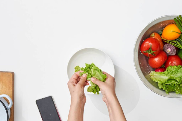 Ansicht einer Frau bei der Zubereitung eines frischen vegetarischen Salats mit - Foto, Bild