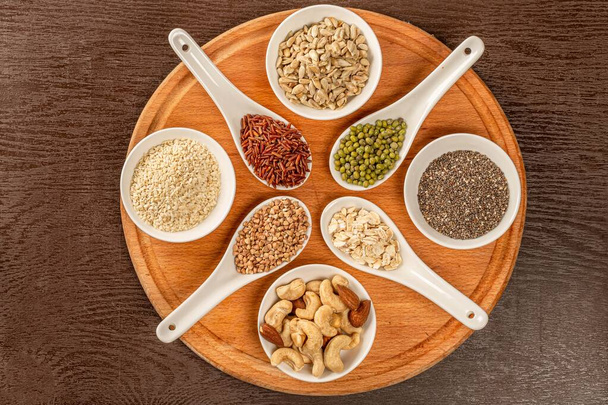 Top view of nuts and seeds in bowls and grains of cereals in spo - Foto, Bild