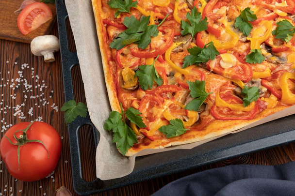 Pizza on myös tomaatteja ja valkosipulia ja paljon muuta mausteita, On myös vihanneksia ja aterioita, tomaatteja, herkullista, ruokaa ja mustaa taustaa. - Valokuva, kuva