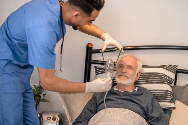 Nurse preparing an aged man for oxygenation - Fotoğraf, Görsel