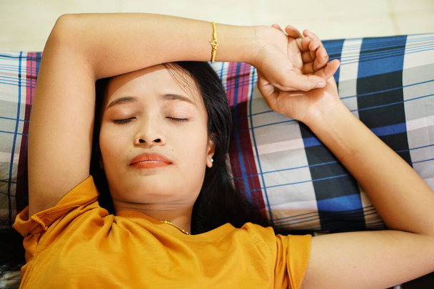 Asian woman in orange shirt sleeping Tired after work - Foto, Imagem