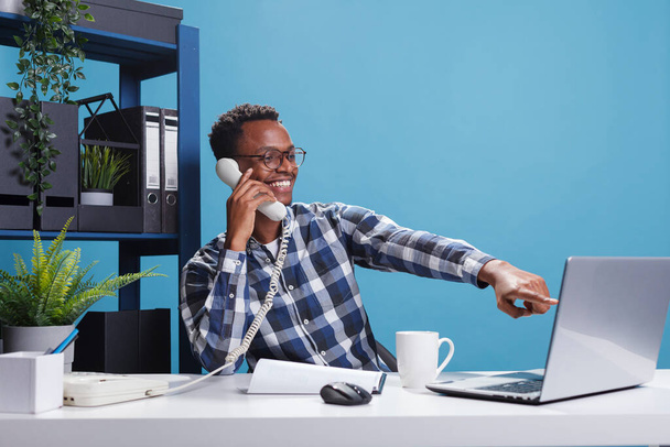 Маркетингова компанія щасливий радісний афроамериканський офісний працівник на стаціонарному телефоні з бухгалтером
 - Фото, зображення