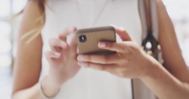 Walking with a connection and confidence in her stride. 4k video footage of a young businesswoman using a cellphone while walking in a modern office. - Felvétel, videó