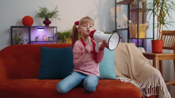 Kindermädchen, die allein zu Hause auf Sofa stehen, rufen laut in Megafon Rabattverkauf an - Filmmaterial, Video