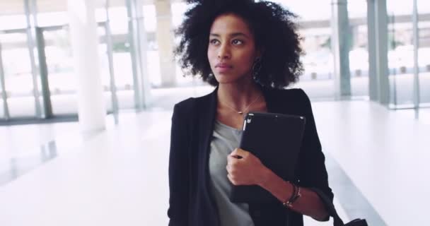 Shes stepping onto a new world. 4k video footage of a confident young businesswoman holding a digital tablet while walking to work inside of a building. - Felvétel, videó