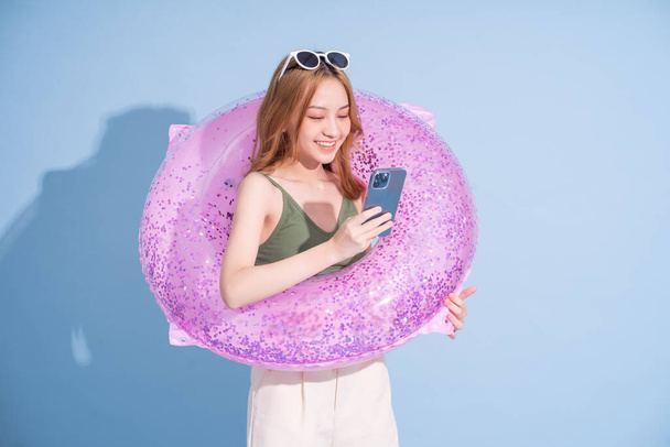 Image of young Asian girl holding swimming float on blue background, summer vacation concept - Foto, Imagem