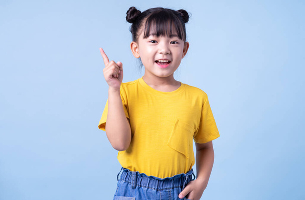 Изображение азиатского ребенка, позирующего на синем фоне - Фото, изображение