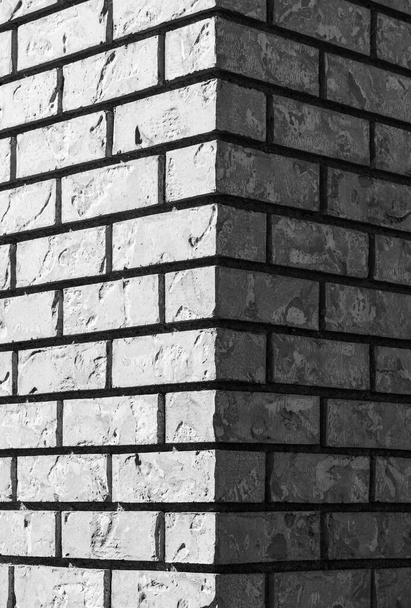 Közelkép a szürke téglafal sarkához. Szürke tégla szürke tégla és tégla széle oszlop előtt a fal, mint textúra háttér - Fotó, kép