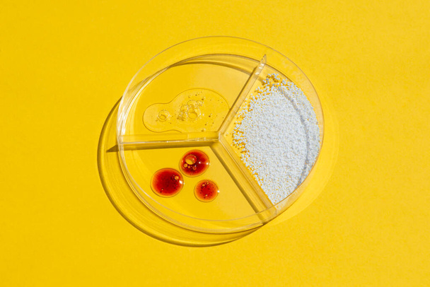 Cosmetic swatches. Appearance of the texture of the cream, red mask, foam and granules in petri dish on a yellow background. Natural skincare products. Beauty concept for face and body care - Photo, image