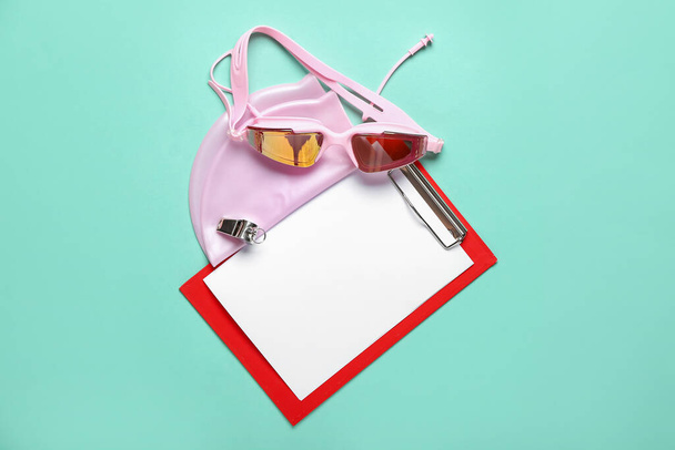 Clipboard with swimming cap and goggles on blue background - Foto, imagen