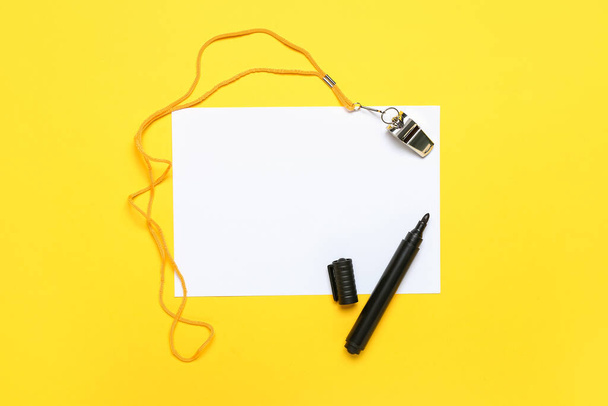 Blank paper sheet with marker and whistle on yellow background - Foto, afbeelding