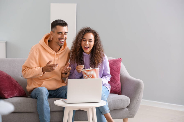 Νεαρό ζευγάρι με ποπ κορν βλέποντας ταινία στο φορητό υπολογιστή στο σπίτι - Φωτογραφία, εικόνα