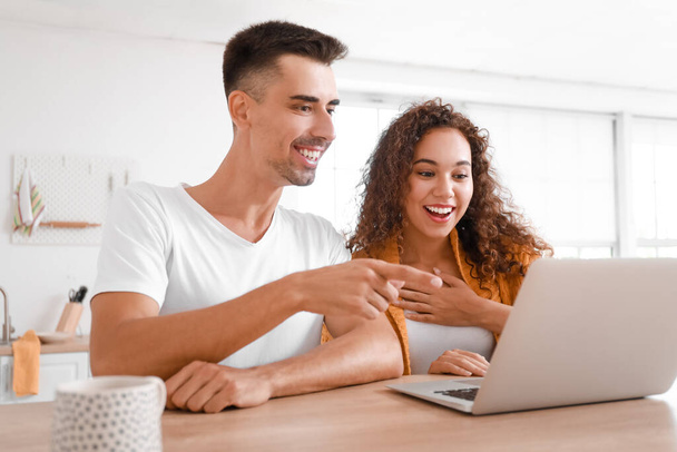 Young couple watching video on laptop in kitchen - Foto, Bild