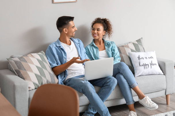 Young couple with laptop video chatting on sofa at home - Foto, Imagem