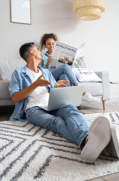 Jongeman met laptop in gesprek met zijn vrouw thuis - Foto, afbeelding