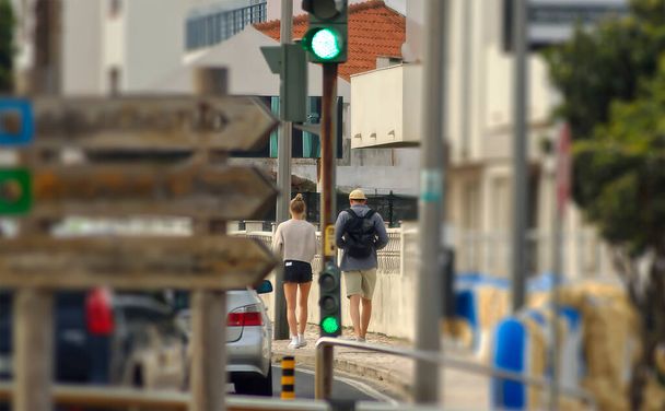 Μερικοί τουρίστες περπατούν στο πεζοδρόμιο μέσα από την πόλη - Φωτογραφία, εικόνα