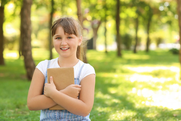 Pieni tyttö kirjan puistossa - Valokuva, kuva