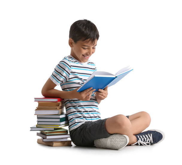 Lindo niño leyendo interesante libro sobre fondo blanco - Foto, Imagen