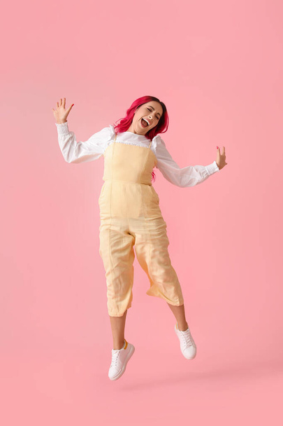 Beautiful woman with bright hair jumping on pink background - Fotó, kép