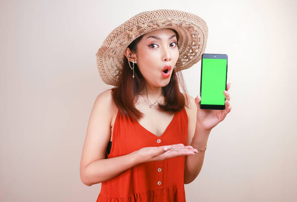 Excited and shocked Asian woman showing screen at smartphone in her hand. - Zdjęcie, obraz