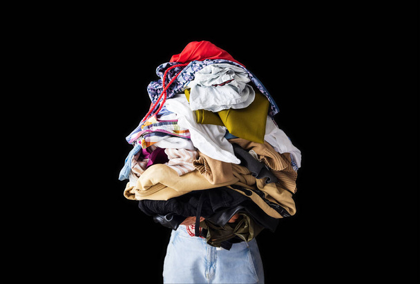 a woman holds a lot of crumpled clothes in her hands, black background, copy-paste - Фото, зображення