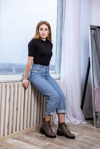Stylish pretty young woman in fashionable clothes with blue jeans and fashionable shoes. Beautiful female legs in leather boots - Φωτογραφία, εικόνα