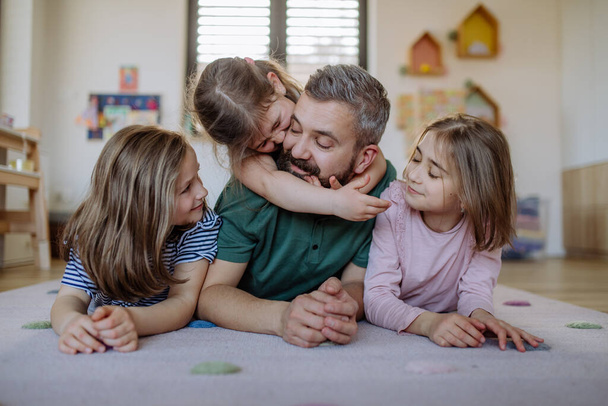 Cheerful father with three little daughters playing together at home. - Fotoğraf, Görsel