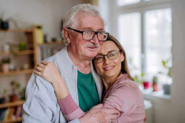 Adult daughter hugging her senior father when visitng him at home. - Photo, Image
