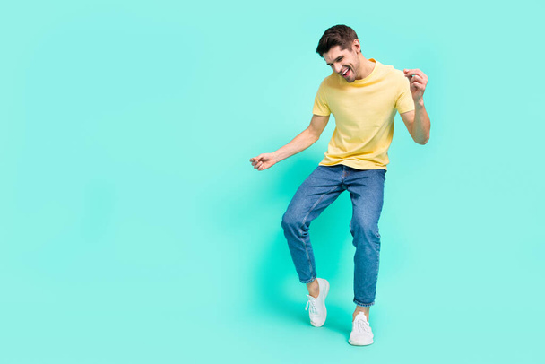 Full size photo of cute brunet young guy dance wear t-shirt jeans shoes isolated on turquoise background - Fotografie, Obrázek