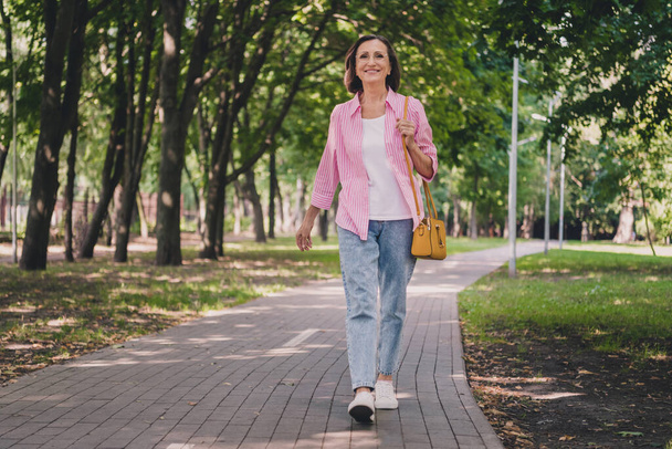 Photo of pretty adorable lady pensioner wear pink shirt walking smiling outdoors countryside garden - Foto, Imagem