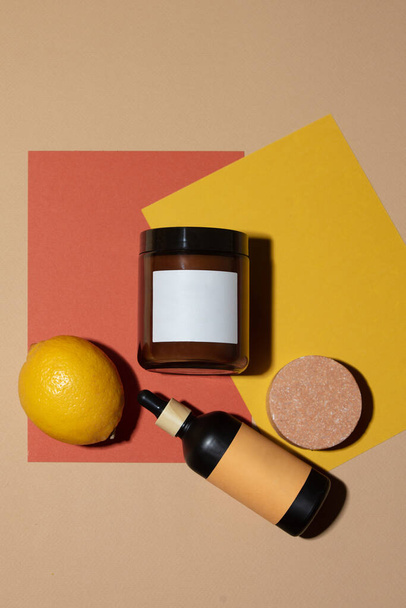Kozmetikai krém tégely és üveg papírlapon citrom mellett - Fotó, kép