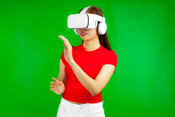 Asian woman in vr glasses, playing video games with virtual reality headset and trying to touch something with hands, isolated green background, Metaverse Concepts - Foto, imagen