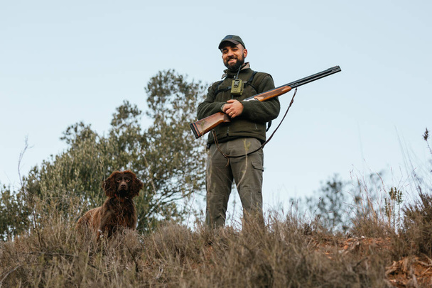 Ritratto di giovane cacciatore in piedi guardando la macchina fotografica insieme al suo cane - Foto, immagini
