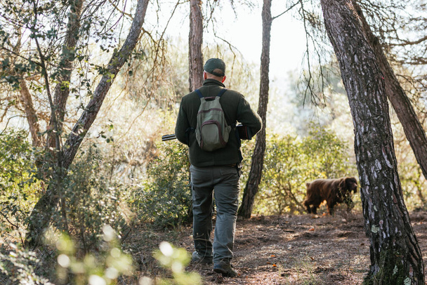 Hunter atento a la caza en el bosque con su perro en frente - Foto, imagen