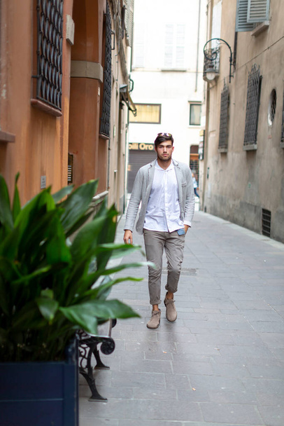 handsome Italian dark-haired guy walks in the center of reggio emilia. High quality photo - Foto, afbeelding