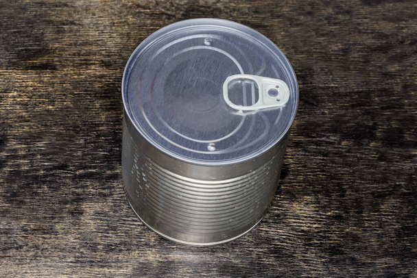 Sealed round tin can of canned vegetable with easy openable lid on the black surface - Foto, Imagen