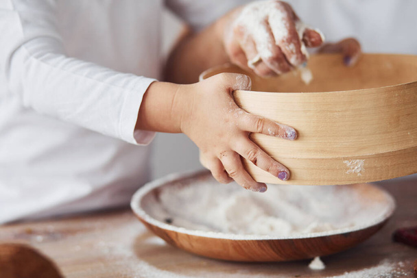 Close up view of woman with her granddaughter preparing food with flour on kitchen. - Foto, Imagem