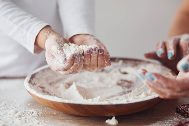 Close up view of woman with her granddaughter preparing food with flour on kitchen. - Foto, Bild