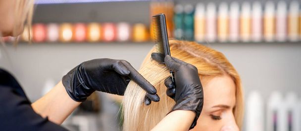 Beautiful young blonde woman with long straight blonde hair getting a haircut at the hairdresser salon - Foto, imagen