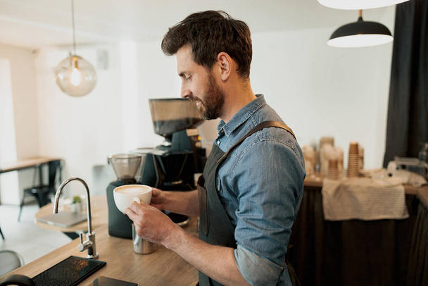 Красива бариста тримає чашку кави перед тим, як віддати клієнту
 - Фото, зображення
