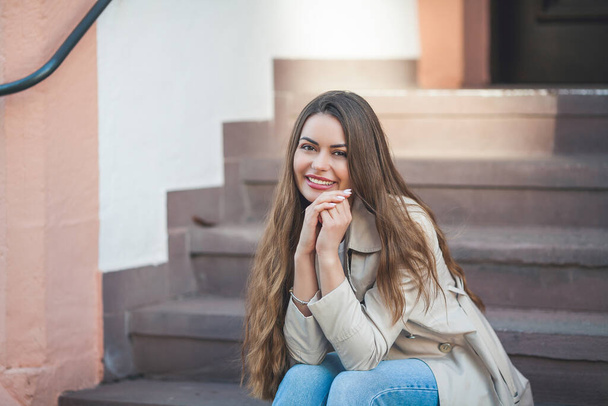 Portrait of a young beautiful long-haired woman in a European city. A model in stylish casual wear is relaxing outside. Spring. - Fotoğraf, Görsel